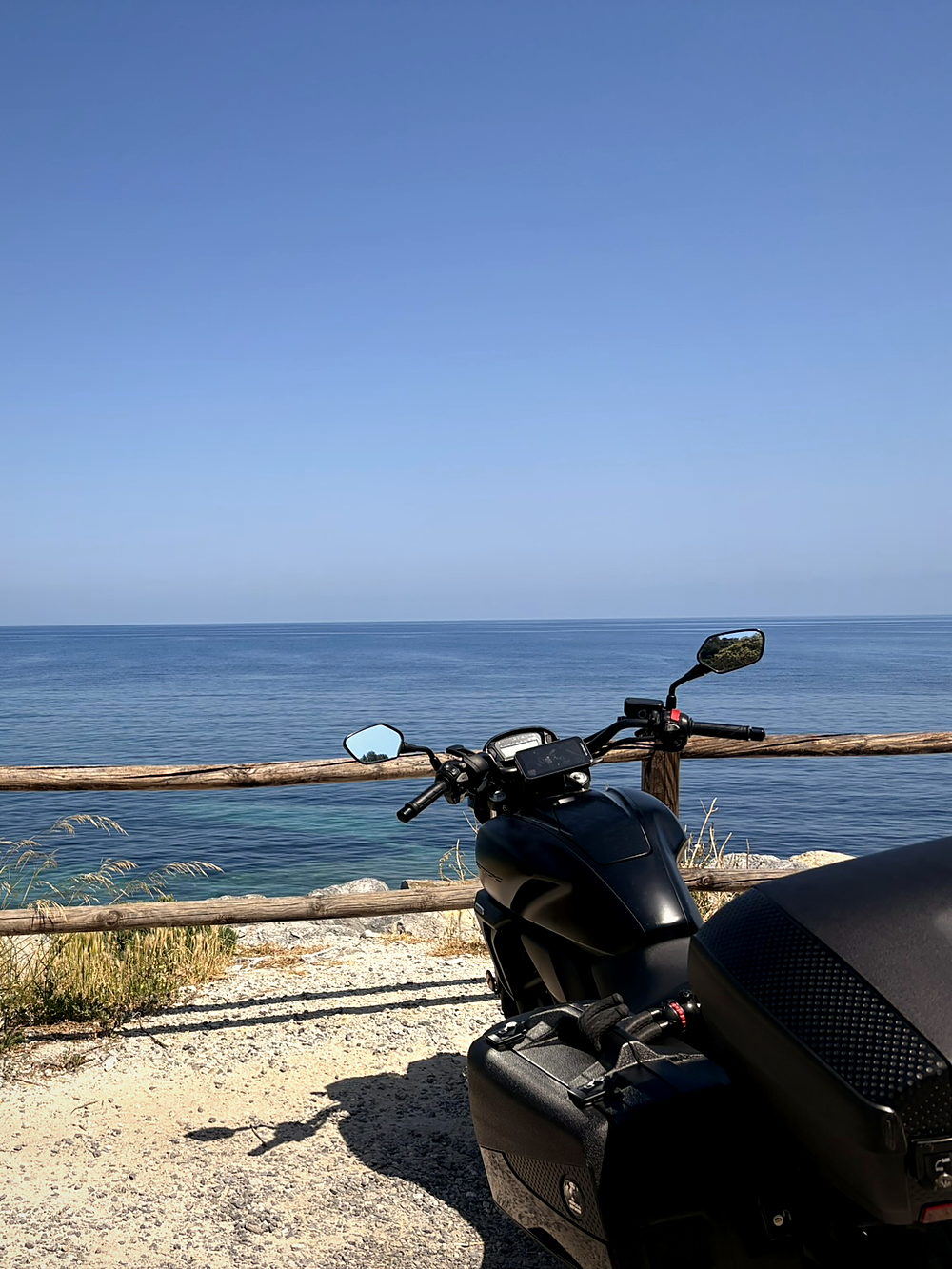 A motorcycle parked at a seaside pull-off on the Via Aurelia above the Ligurian sea