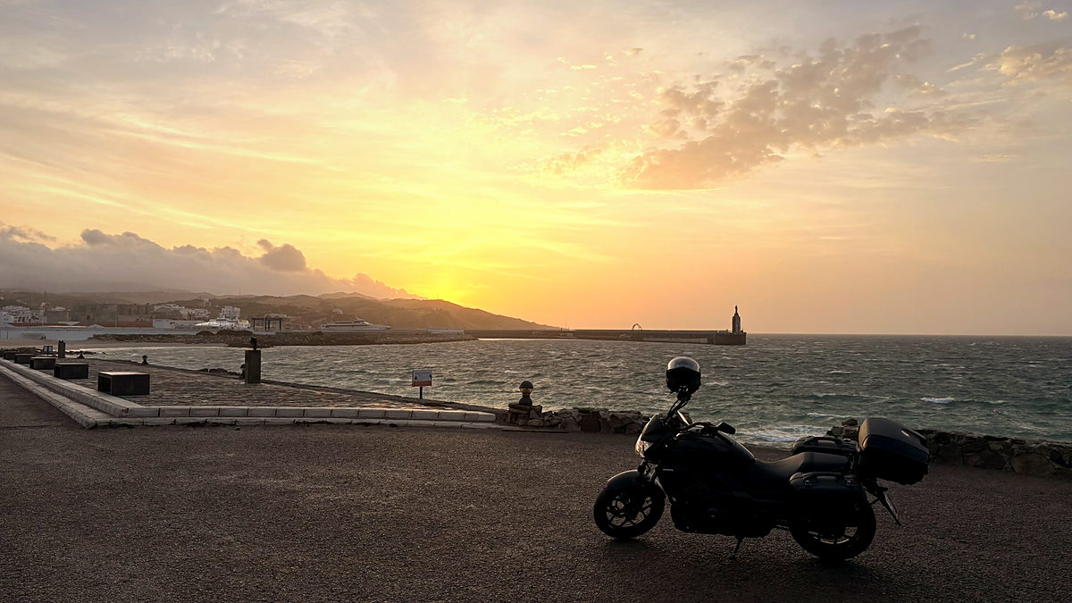 Sunrise over the sea at Tarifa with a loaded motorcycle on the quay