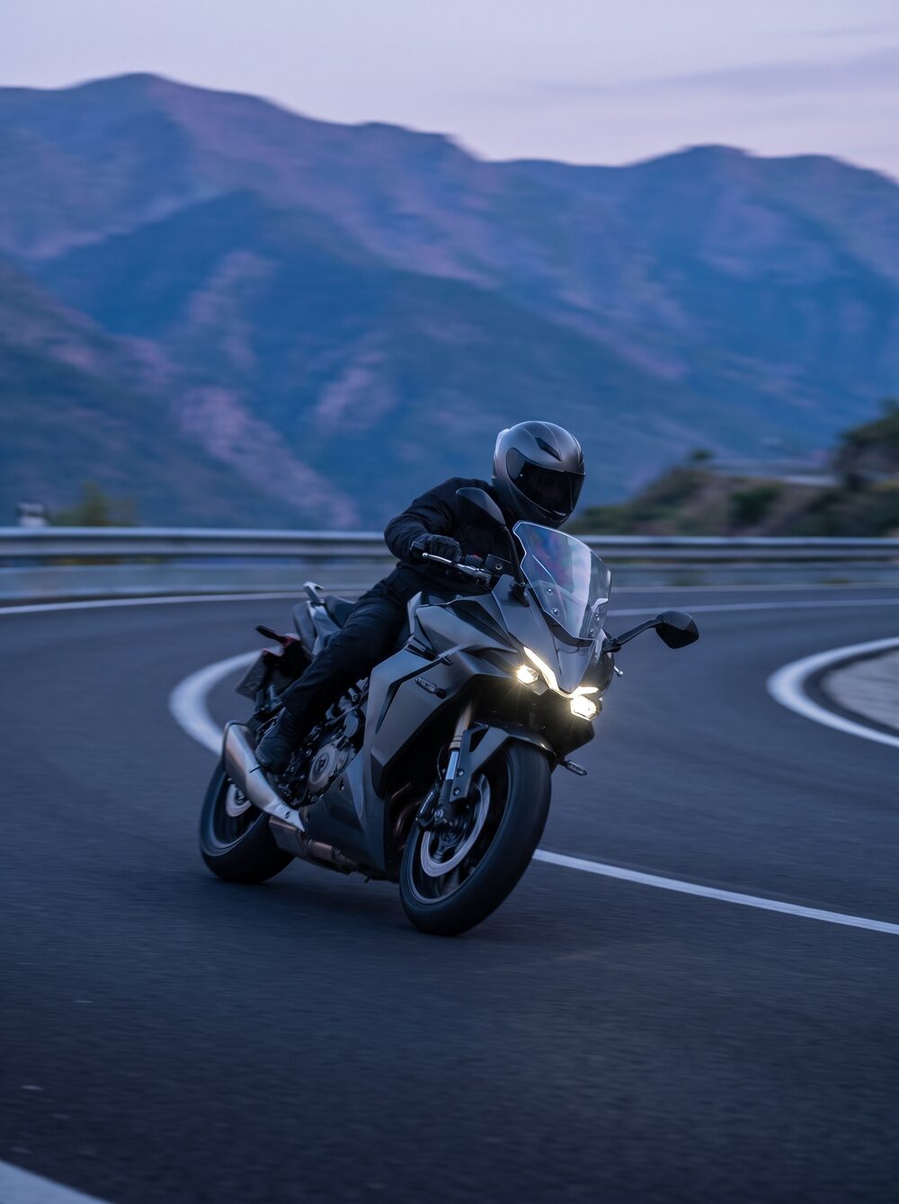 Sport-touring motorcycle leaned deep into a mountain hairpin at dusk
